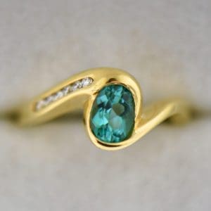 custom 18k yellow gold swirl ring with bezel set teal tourmaline