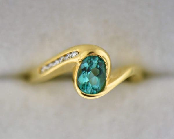 custom 18k yellow gold swirl ring with bezel set teal tourmaline