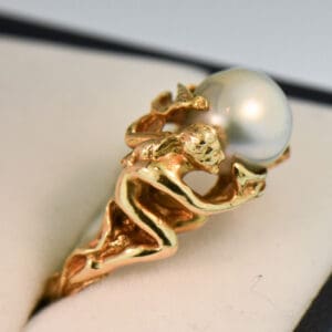 carved artsy gold ring with pixie or sprite holding pearl
